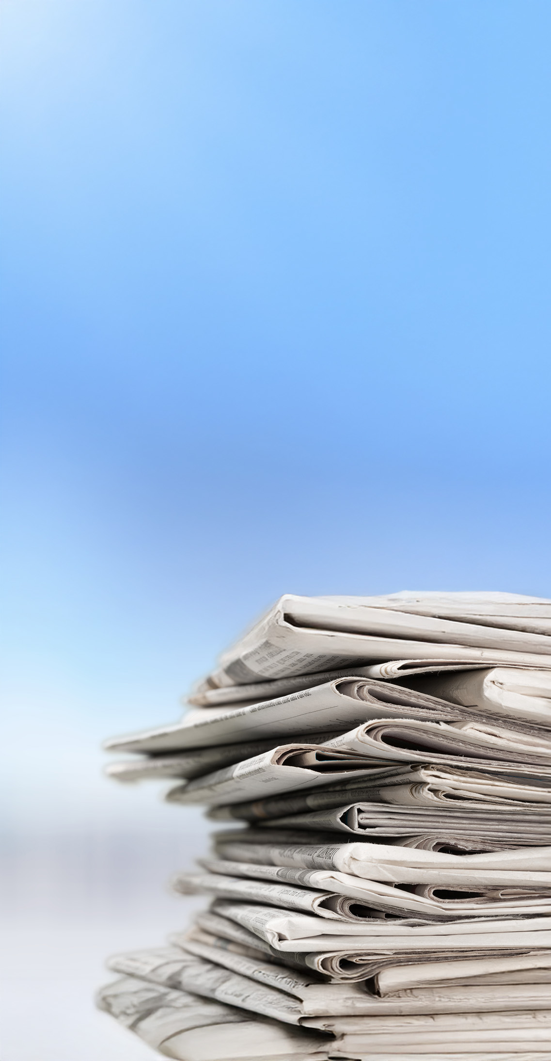 A stack of print media, showcasing various newspapers