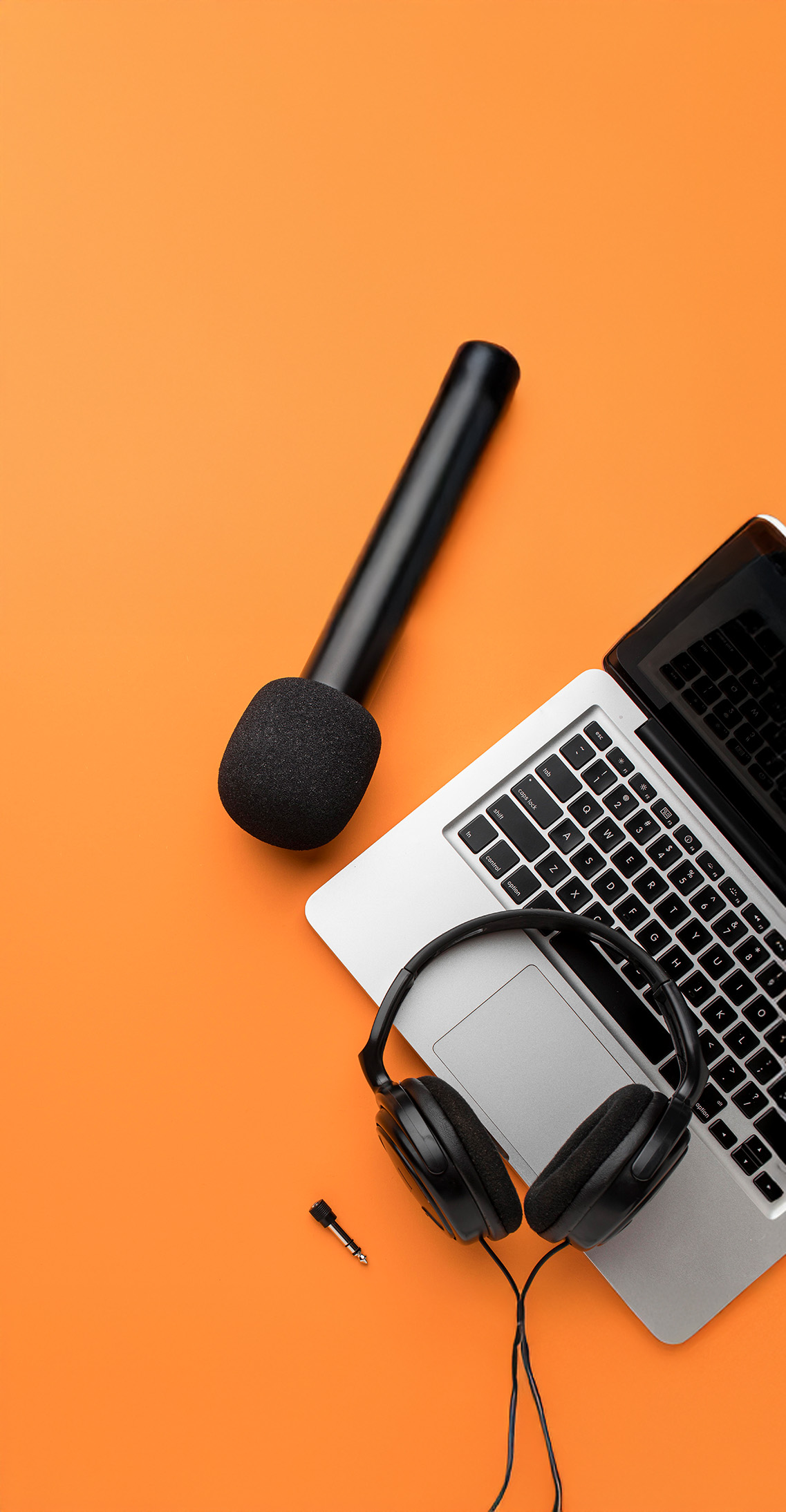 Audio gear including a microphone and headphones on an orange background